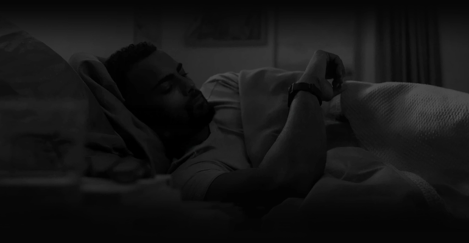 A man lying in bed looks at his Zeblaze Stratos 4 smart watch